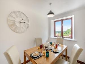 a dining room with a table and a clock on the wall at Holgates in Upottery