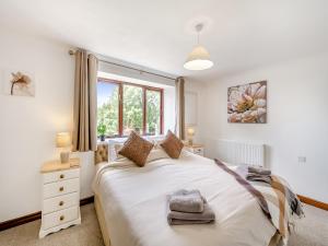 a bedroom with a large white bed with a window at Holgates in Upottery