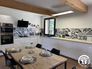 a kitchen with a wooden table and chairs in it at Les mains du soleil in Millas