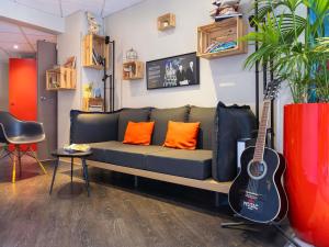 a living room with a couch and a guitar at ibis Metz Nord in Woippy