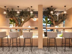 a lobby with a table and chairs and trees at Novotel Macon Nord - Porte de Bourgogne in Mâcon