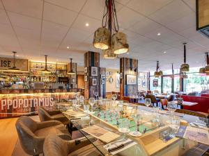a restaurant with a glass table and chairs at Novotel Bordeaux Mérignac in Mérignac