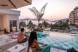 a group of people sitting around a swimming pool at Hotel Oasis in Sarandë