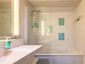 a bathroom with a shower and a sink and a tub at Novotel Dijon Sud in Dijon +112 photos