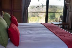 a bed with red and green pillows and a window at Mohlabetsi Self Catering Bush Lodge in Balule Game Reserve