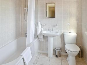 a bathroom with a toilet and a sink and a bath tub at Weetwood Lodge in Kelsall +2 photos