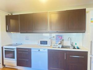 a kitchen with wooden cabinets and a white microwave at Cozy 2-Bedroom Apartment in Kristiansand