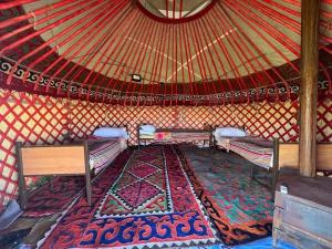 a room with two beds and a rug in a yurt at Kambar-ata yurt camp in Song-Kul