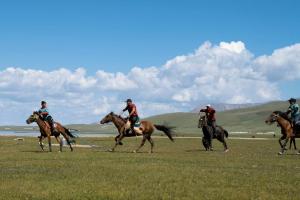 a group of people playing a game of polo on horses at Kambar-ata yurt camp in Song-Kul