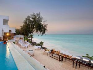 a restaurant on the beach next to a swimming pool at Nungwi Dreams by Mantis in Nungwi