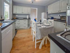 a kitchen with white cabinets and a table with chairs at Station House in St Bees