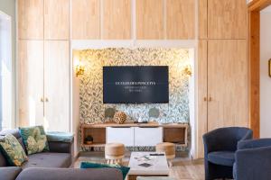 a living room with a couch and a tv on a wall at Le Clos des Poncétys - gîte de charme avec piscine dans les vignes de Bourgogne in Davayé