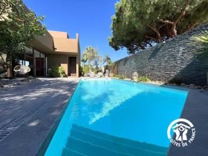 a blue swimming pool in front of a house at L'hacienda in Pia