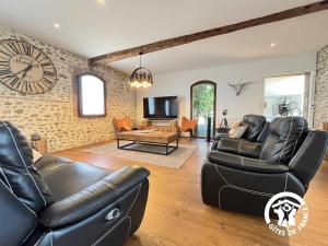 a living room with black leather furniture and a clock at L'hacienda in Pia