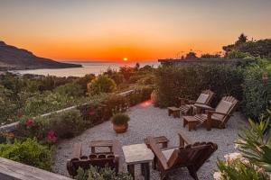 a patio with chairs and a sunset in the background at Terra Minoika Boutique Resort in Kato Zakros