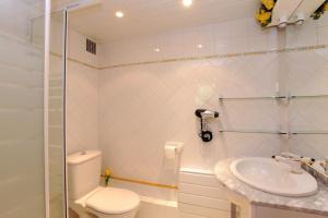 a white bathroom with a toilet and a sink at Les lauriers in Sahorre