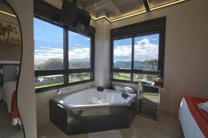 a bathroom with a large tub in a room with windows at Pousada Premium Terragnolo in Bento Gonçalves