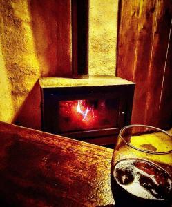 a glass of wine sitting on a table with a fireplace at Kamiare in San Esteban