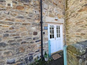 a door to a stone house with a stone wall at Eden's House in Hexham