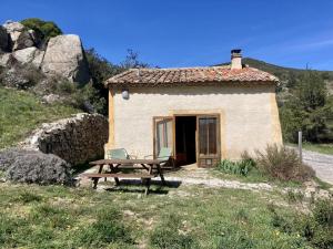 a small stone house with a picnic table and a bench at Le gîte de l'encantade in Trévillach