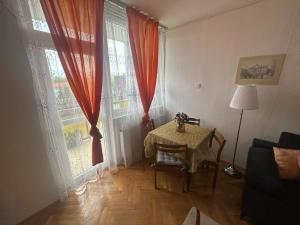 a living room with a table and two large windows at Digitális Detox Apartman in Tiszafüred