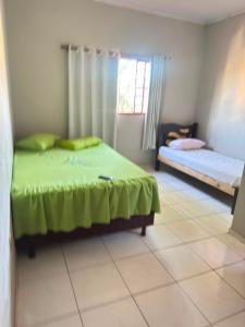 a bedroom with a green bed and a window at Pousada Marialva in Barreiras