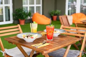 a wooden table with plates of food and drinks on it at Airport Hotel Budapest in Vecsés