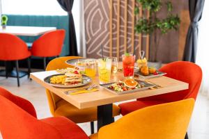 a table with plates of food on it with orange chairs at Airport Hotel Budapest in Vecsés +77 photos