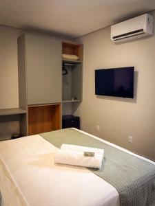 a bedroom with a bed and a flat screen tv at Uai Hotel Jaíba in Terra Fôfa