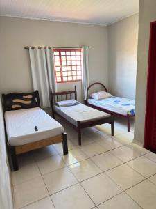 a room with two beds and a chair and a window at Pousada Marialva in Barreiras
