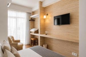 a hotel room with a bed and a tv on a wall at Hotel Vice-Rei in Porto