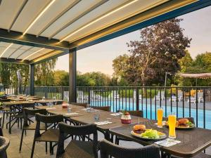 a restaurant with tables and chairs and a pool at Novotel Roissy Saint Witz in Saint-Witz