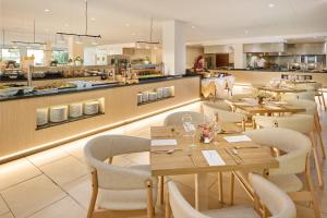 a restaurant with tables and chairs and a kitchen at Grupotel Mallorca Mar in Cala Bona