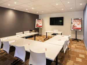 a conference room with white tables and chairs and a flat screen tv at ibis Montpellier Sud in Montpellier