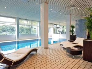 a pool room with two beds and a pool at Mercure Hotel Köln West in Cologne