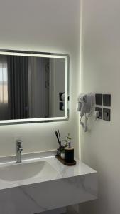 a bathroom with a white sink and a large mirror at شقة بغرفتين نوم وصالة in Hail