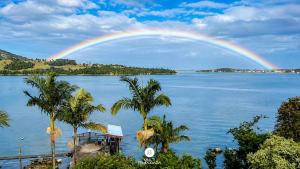 a rainbow over a body of water with palm trees at Casa na Lagoa - Imaruí/SC in Imaruí