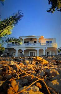 a house on the beach with a pile of rocks at Villa Andale Suites in Tkon