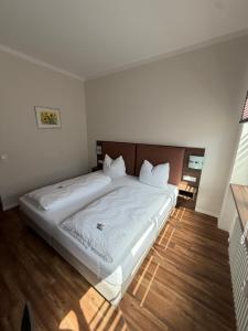 a bedroom with a large white bed with a wooden headboard at Hotel zur Post - Schrobenhausen in Schrobenhausen