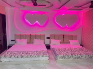two beds in a pink room with hearts on the wall at Radhika Cozy Studio Apartment Kitchen 2 Double Beds in Vrindāvan +5 photos