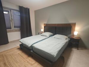 a bed in a bedroom with two night stands and two windows at Gästehaus Ferienwohnung Zimmer 2A Jülich in Jülich