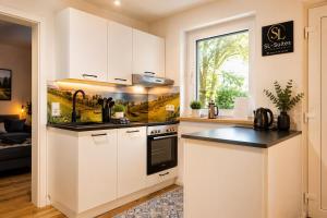 a kitchen with white cabinets and a black counter top at Neues 2 Zimmer Schmuckstück in Ergetsweiler