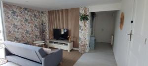 a living room with a couch and a tv at Le Petit Nid de Mombrier in Mombrier