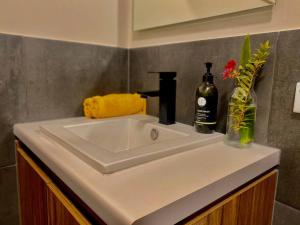 a white sink with a bottle of wine and a vase of flowers at Boutique Room - Wamoon Retreat in Yanakie +17 photos