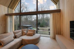 a living room with a couch and a large window at Lodge with Jacuzzi | 6 persons in Heusden - Zolder