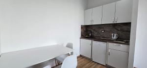 a white kitchen with white cabinets and a table at Beachfront Blue Panorama in Bar