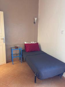 a bed with a red pillow and a side table at Maison Sevilla in Larache
