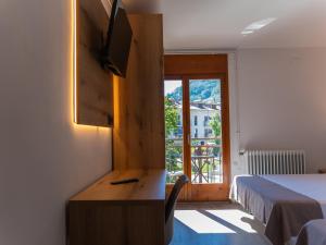 a room with a desk with a television and a bed at El 9 Baral-la in Sant Pau de Segúries