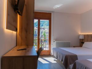 a room with two beds and a desk and a window at El 9 Baral-la in Sant Pau de Segúries