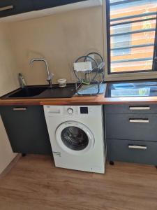 a kitchen with a sink and a washing machine at Le Ghirol - Tiny Houses & Nature in Quesnel